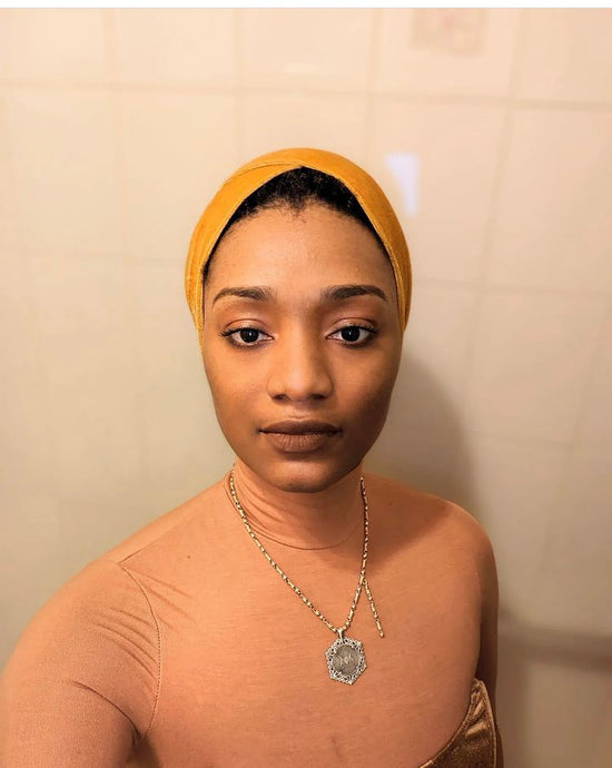 African American woman wearing a gold head wrap with a necklace