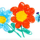 A colorful children's crayon drawing of flowers and a butterfly on a white background, featuring a large orange-red flower with a yellow center, a smaller blue flower with a yellow center, green stems and leaves, and a blue-and-purple butterfly.