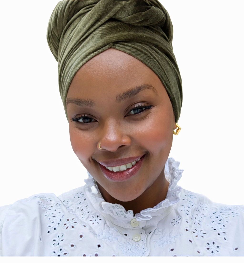 Woman wearing an olive headscarf and white blouse against a white background