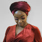 Woman leaning forward with head turban burgundy or red color with a smirk